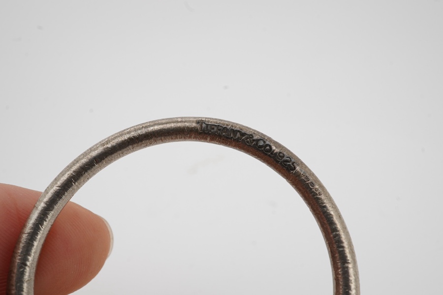 Tiffany & Co, a silver scarf ring, of torque design with a hanging tag, signed Tiffany & Co., British hallmarks, sponsor's mark T&Co., length 4.5cm excluding tag, gross weight 22 grams, pouch and box stamped Tiffany & Co